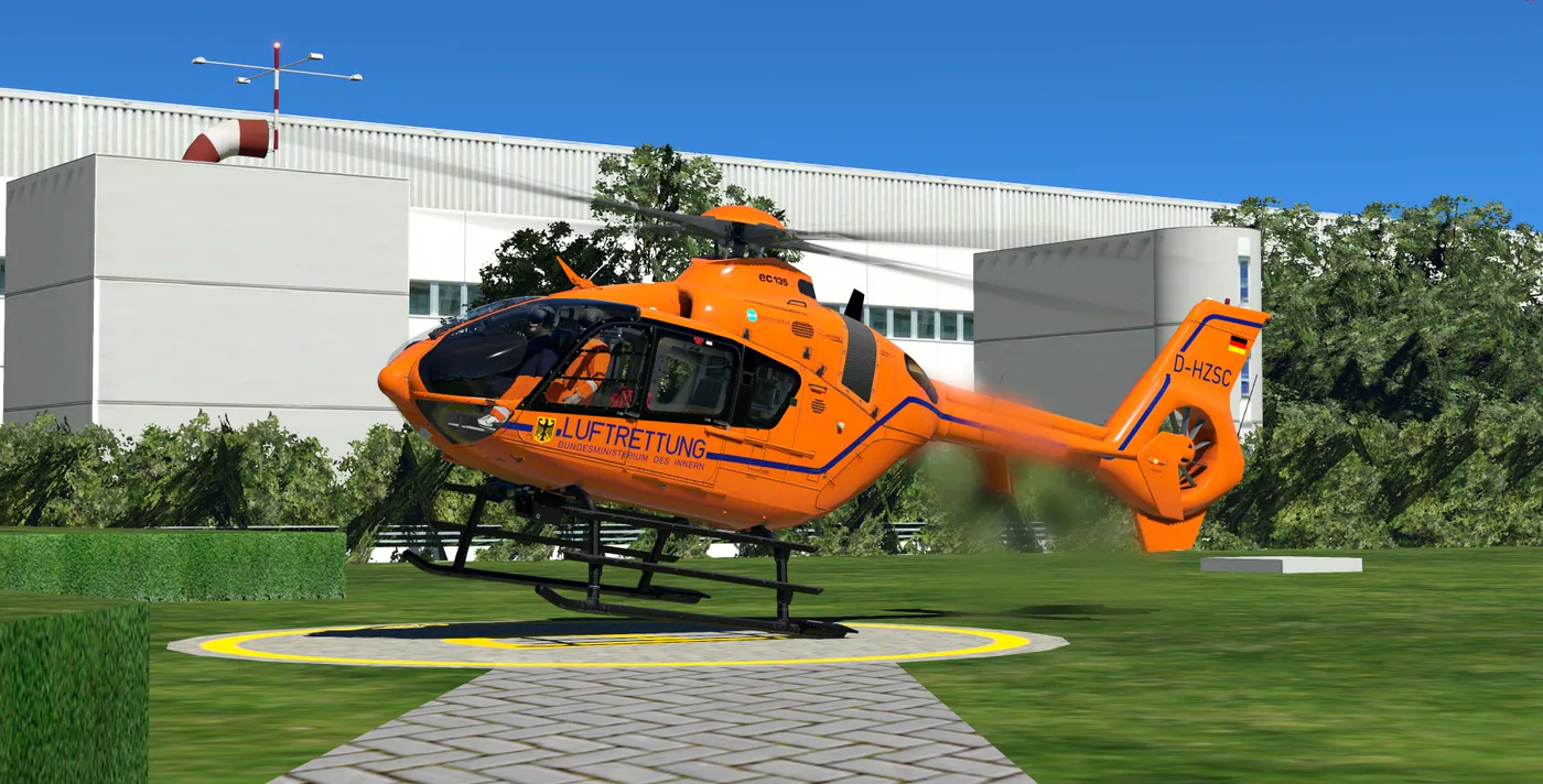 Orange EC135 der BMI-Luftrettung hebt von einem Landeplatz an einer Klinik ab