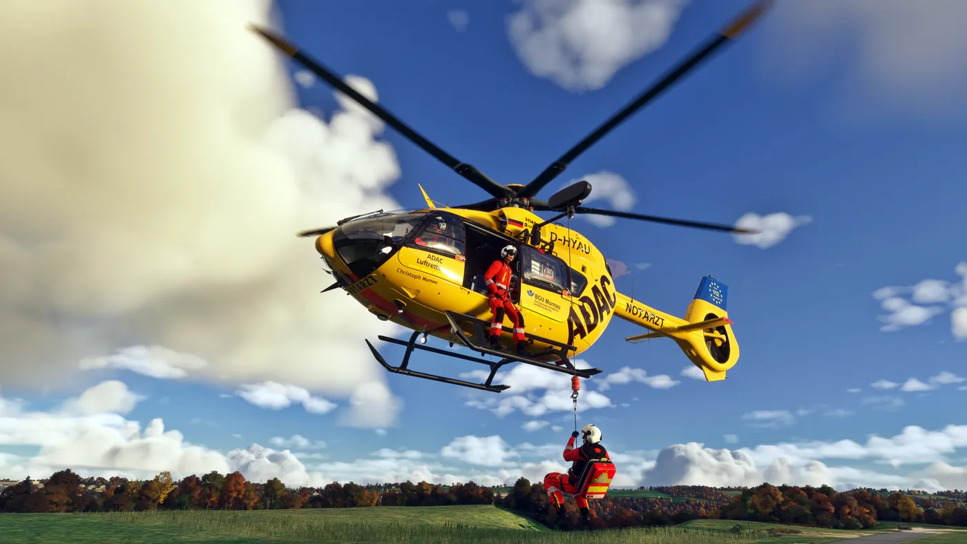 Gelber ADAC-Hubschrauber im Schwebeflug, ein Retter hängt an der Winde
